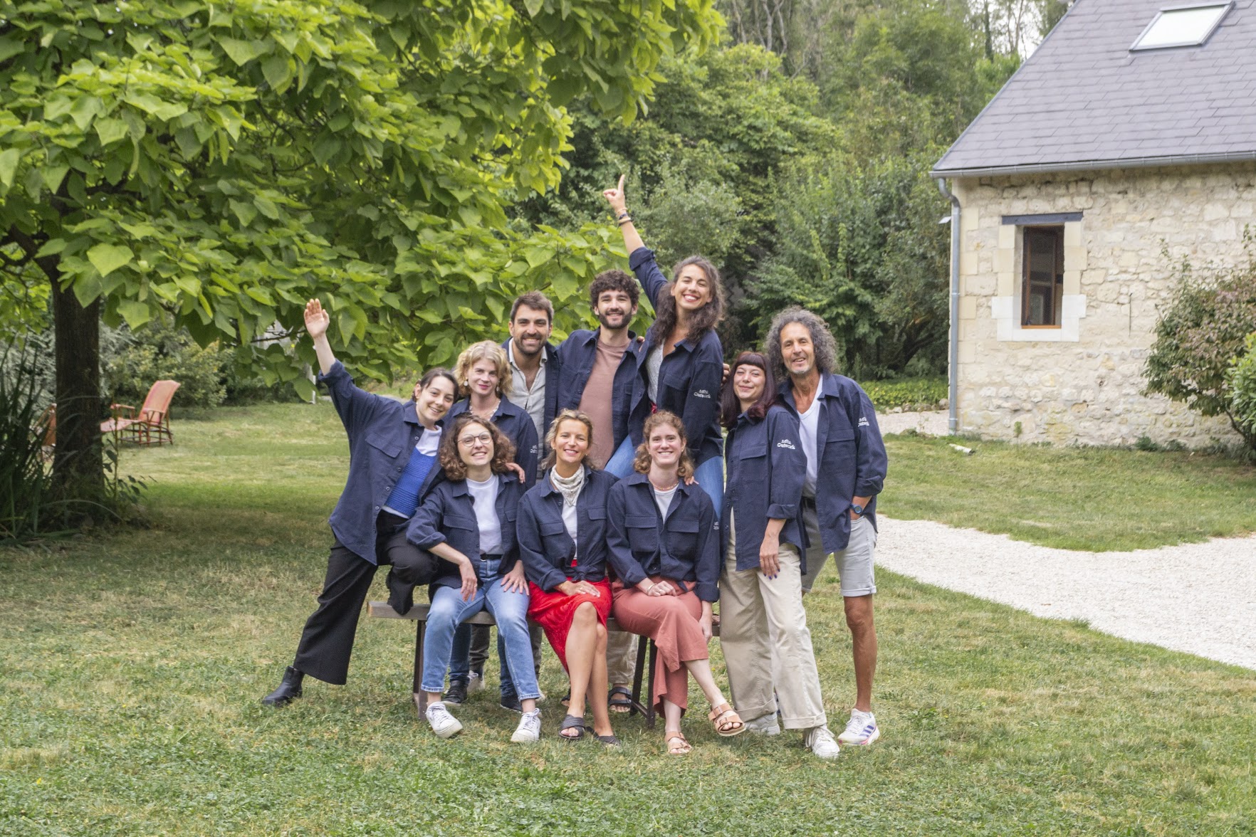 L'équipe Outwork rassemblée dans un jardin, bras levés et souriants.